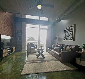 Ein Wohnzimmer mit Fernseher, Sofa, Couchtisch und Kunstwerk an der Wand.