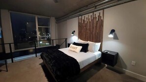 Ein Schlafzimmer mit Bett, Nachttischen, Fenster und Balkongeländer.