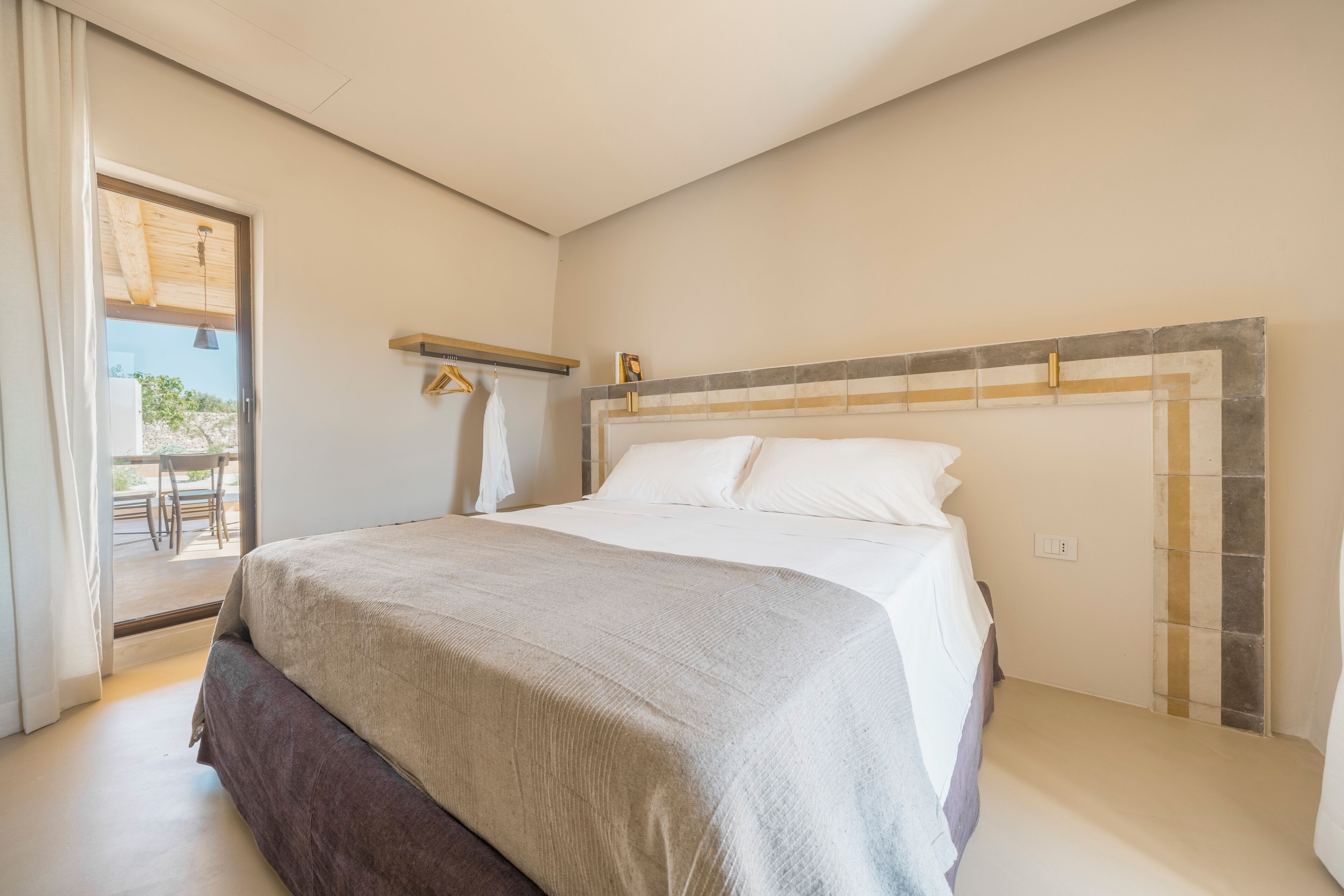 A bedroom with a bed, a window, a door, and a small table with chairs.