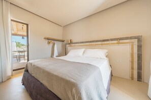 Un dormitorio con cama, ventana, puerta y una pequeña mesa con sillas.