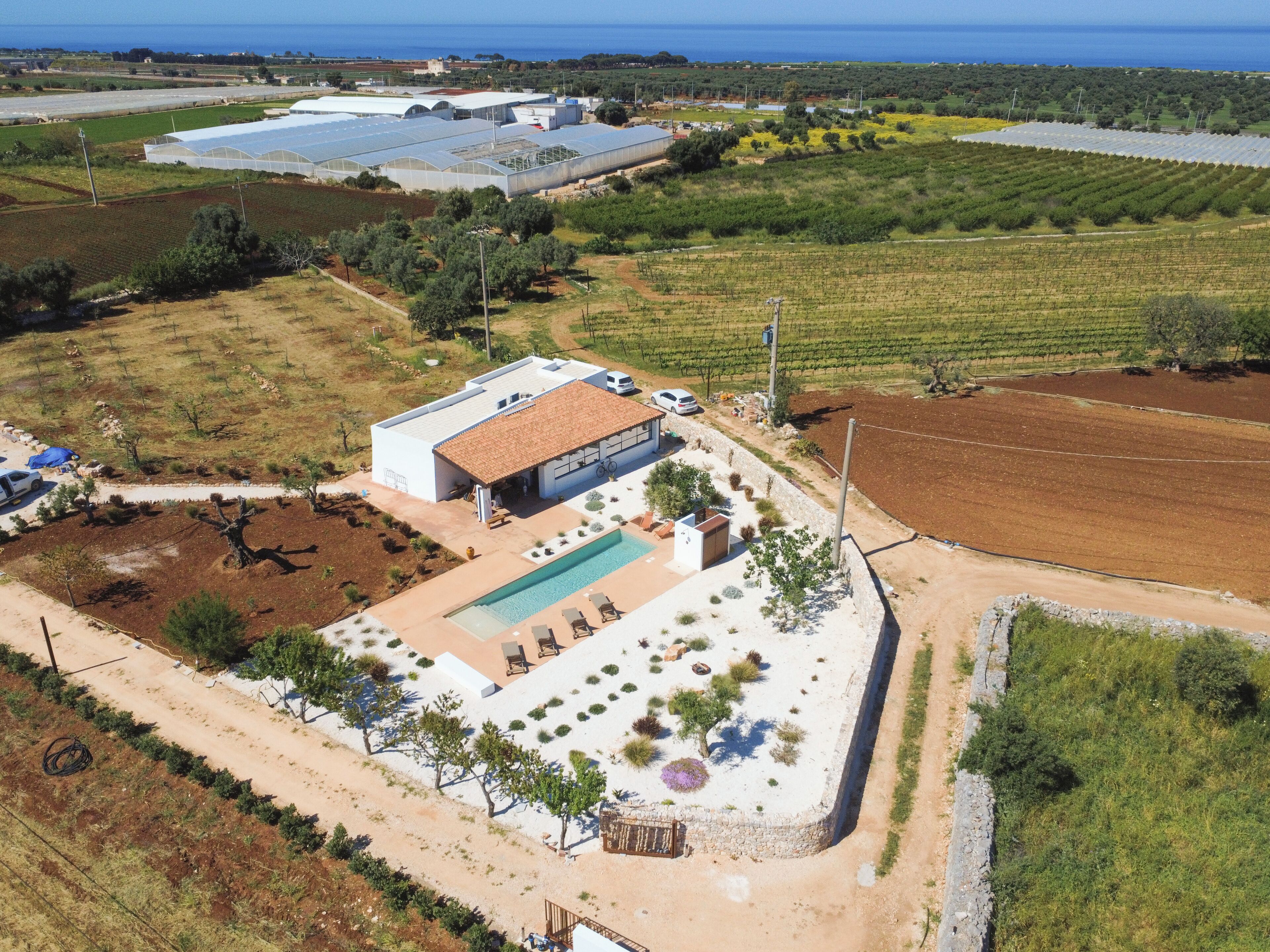 Un edificio grande con piscina, rodeado de jardines ajardinados y campos.