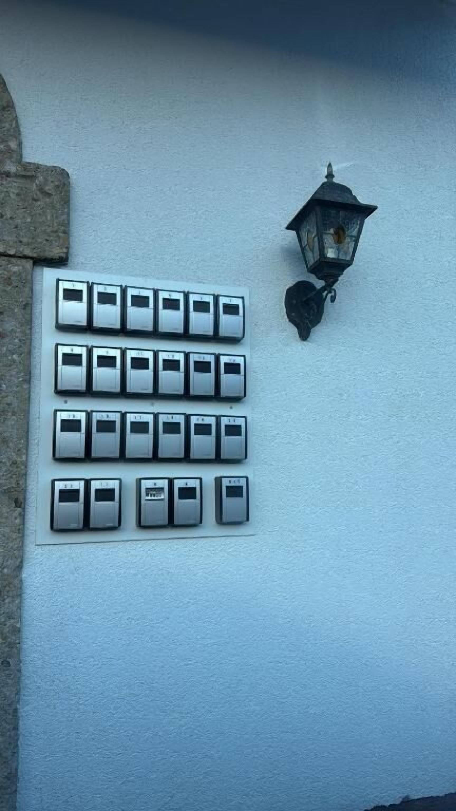 A wall-mounted light fixture and a row of doorbell buttons.