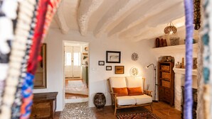 Un saló acollidor amb un sofà, una llar de foc i un passadís que condueix a una altra habitació.