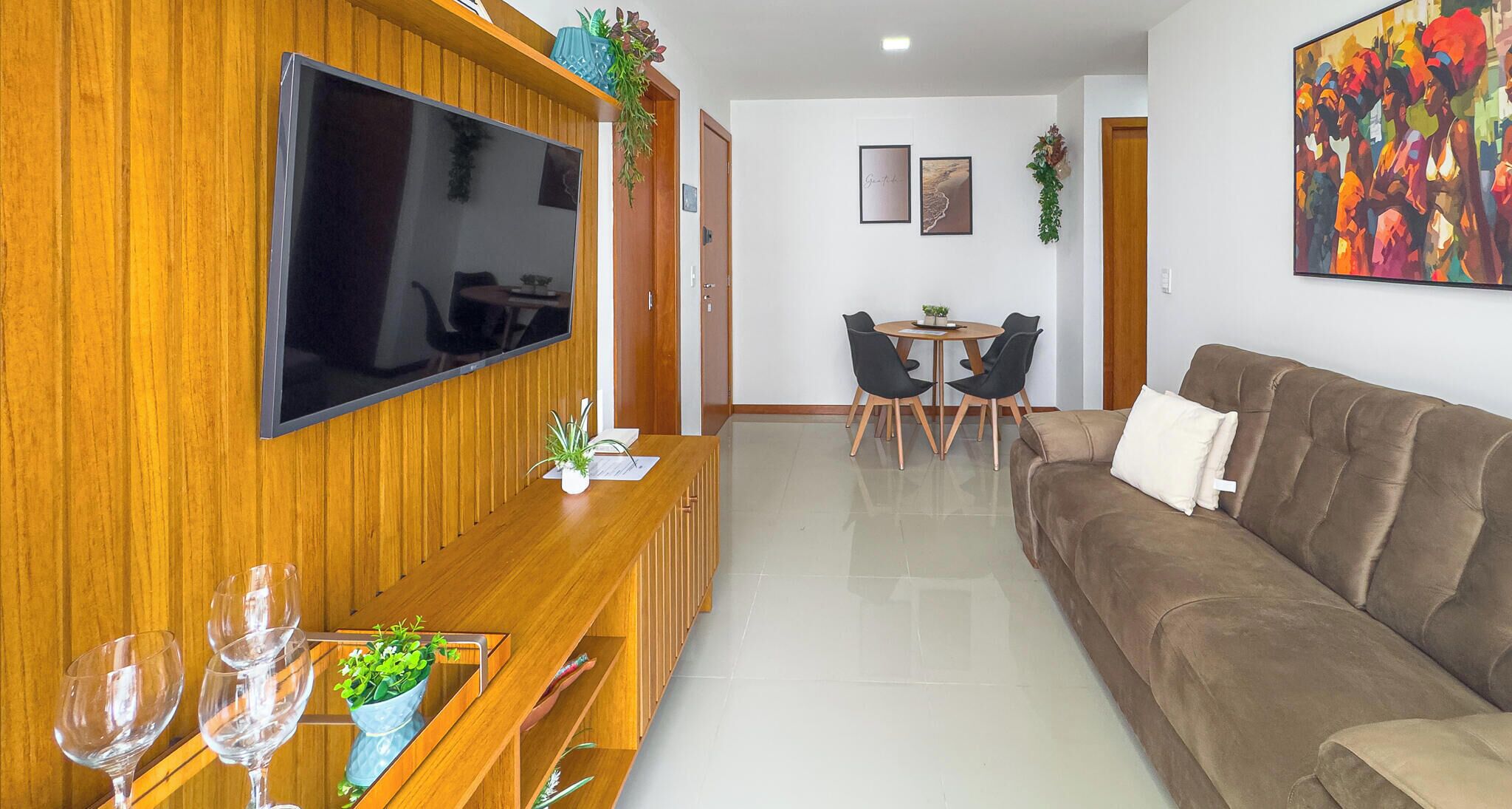 A living room with a TV, sofa, dining table, chairs, and a coffee table.