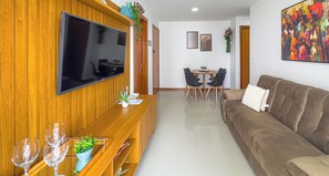 Una sala de estar con televisor, sofá, mesa de comedor, sillas y una mesa de centro.