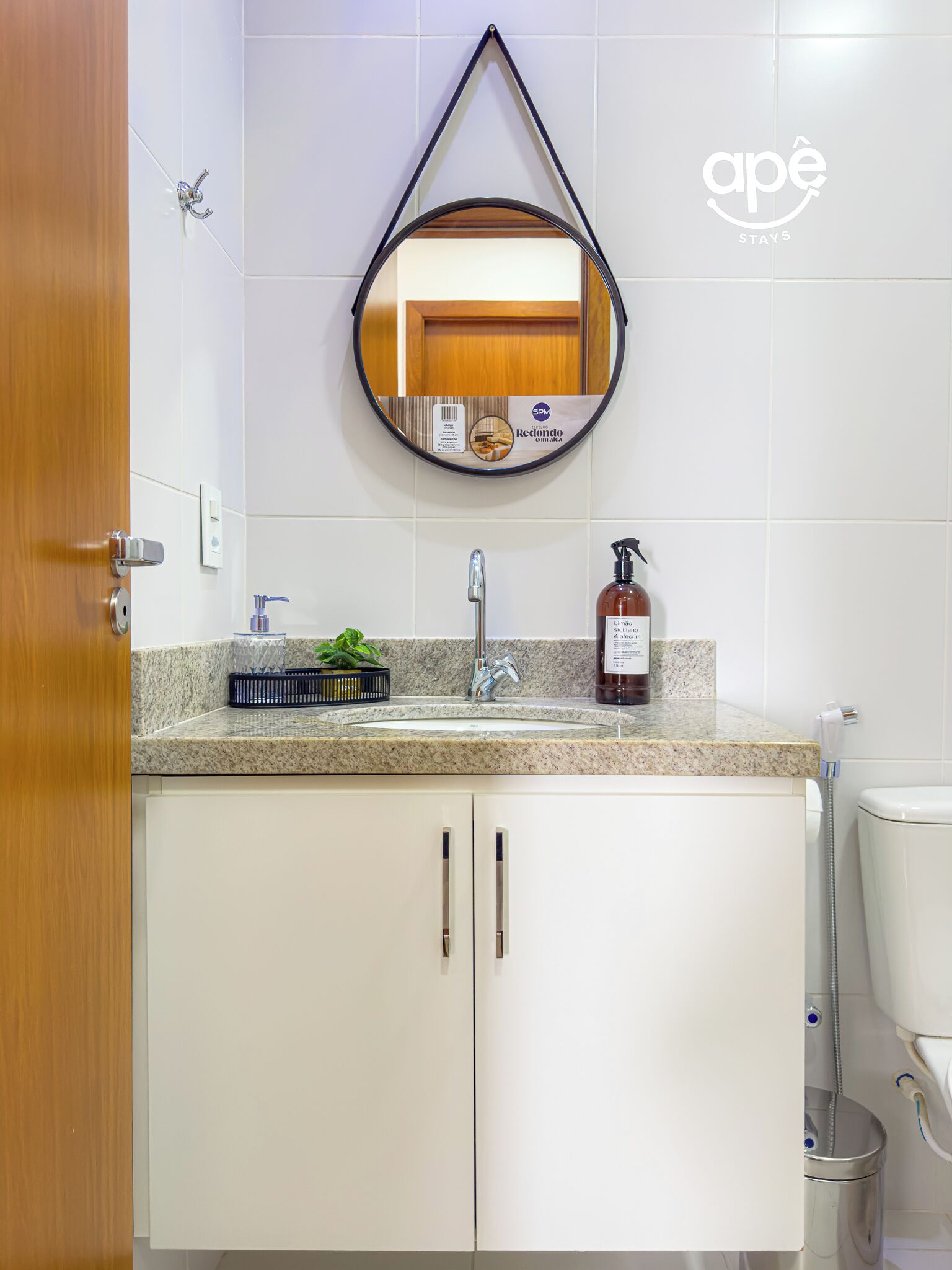 A bathroom with a sink, mirror, toilet, and a hanging towel rack.