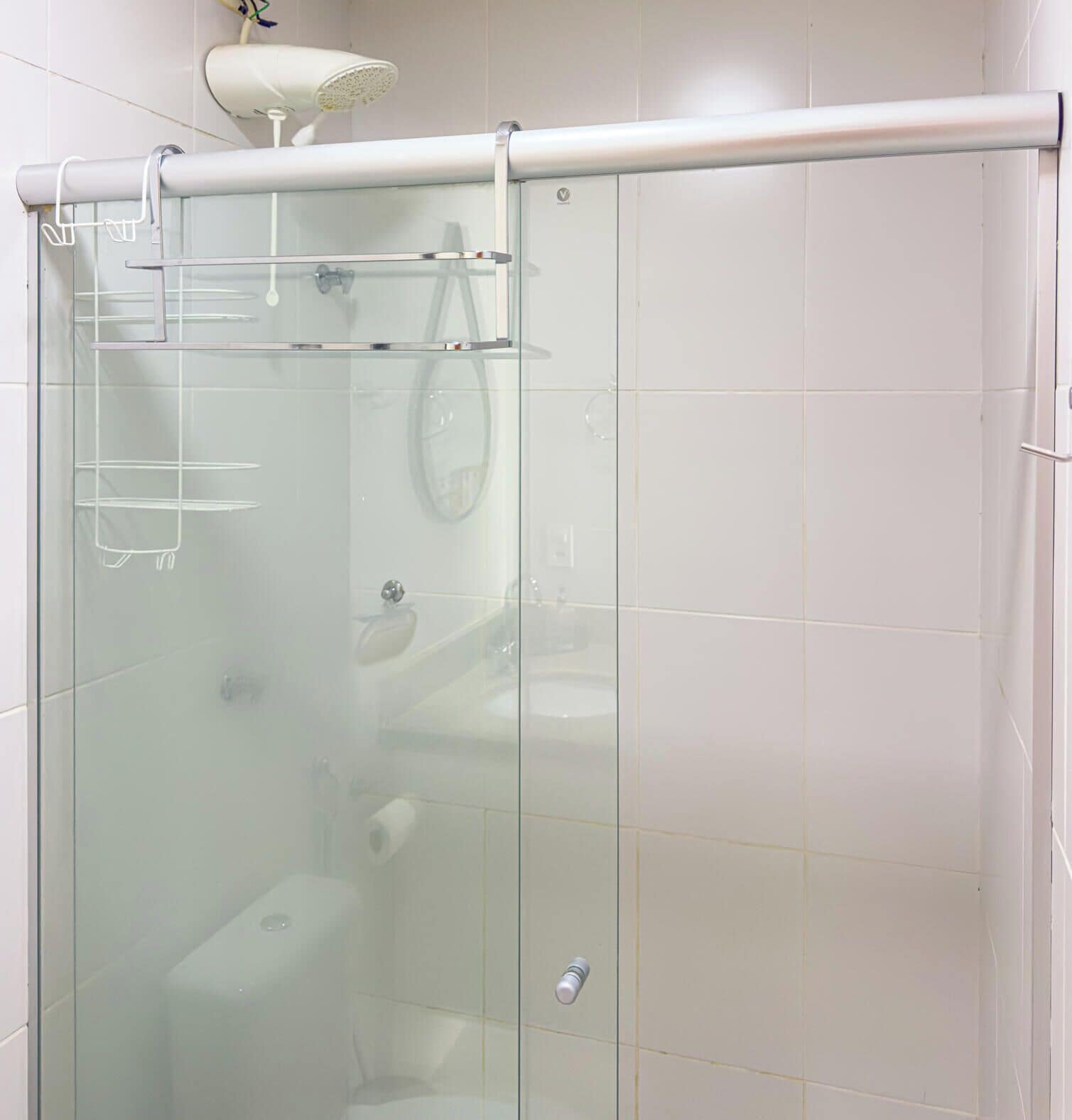 Une cabine de douche fermée par des parois en verre, dotée d’un pommeau de douche blanc et d’un porte-serviettes.
