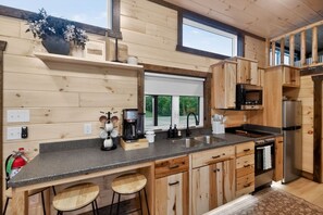 Eine moderne Küche mit Holzschränken, einer schwarzen Arbeitsplatte, einer Kaffeemaschine und einem Spülbecken.