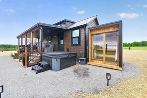 Ein modernes Haus mit einer Veranda, einer kleinen Sitzgelegenheit im Freien und einer Glasgleittür.