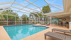 Une piscine intérieure dotée d’un toit en verre, de chaises longues et offrant une vue sur les environs.