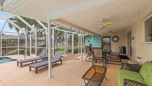 Un espace extérieur abrité comprenant des chaises longues, une piscine et une table.