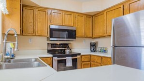Eine Küche mit Holzschränken, einem Edelstahlkühlschrank, einer Mikrowelle, einem Backofen und einem Spülbecken.