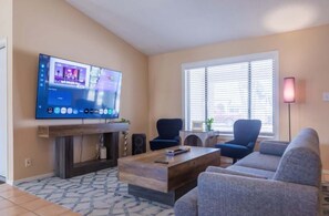 Ein Wohnzimmer mit Flachbildfernseher, Kamin, Sofa und Couchtisch.