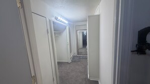 A hallway with a light fixture, a door with a hanger, and a closet.