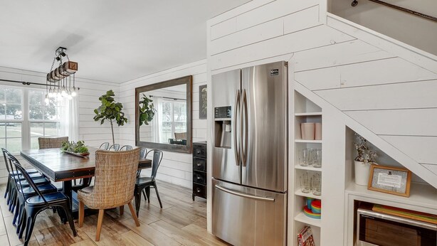 Eine moderne Küche mit einem Edelstahl-Kühlschrank, einem Holztisch und Stühlen.