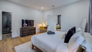 Ein Schlafzimmer mit Bett, Fernseher, Schreibtisch und Spiegel.