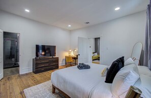 A bedroom with a bed, a TV, a desk, and a mirror. - Cheerful & Central 1-bd/1-ba w Backyard (Houston)