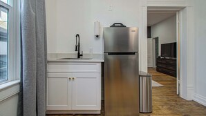 Eine Küche mit einem Edelstahl-Kühlschrank, einer Spüle und einem Mülleimer.