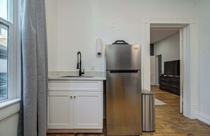 A kitchen with a stainless steel refrigerator, a sink, and a trash can. - Cheerful & Central 1-bd/1-ba w Backyard (Houston)