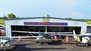 A hangar labeled 'Dallas SkyDive Center' with multiple small aircraft parked inside. - 5-bd/2.5-ba With Pool, Hot Tub, Cinema & Golf Sim (Royse City)