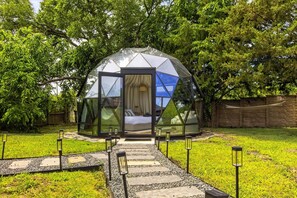 A geodesic dome structure with a glass entrance, a bed inside, and a pathway leading to it. - 5-bd/2.5-ba With Pool, Hot Tub, Cinema & Golf Sim (Royse City)