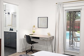 Ein Hotelzimmer mit Schreibtisch, Stuhl, Bett und Blick auf einen Pool durch das Fenster.