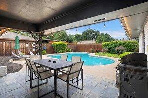 An outdoor patio with a pool, a grill, and a table with chairs. - Spacious 5BR - Pool, Backyard - Upscale Dallas Home (Dallas)