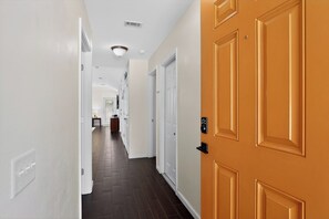 A hallway with a wooden door, white walls, and a dark floor. - Sun, Safari, Shopping- 3 BR Escape, Drive to Beach (Gulf Breeze)