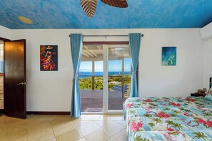 Ein Schlafzimmer mit Bett, Blick durch eine Schiebetür und Kunstwerken an den Wänden.