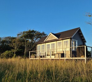 Ein Haus mit Veranda, großen Fenstern und einem überdachten Bereich.