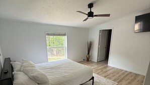 A bedroom with a bed, a ceiling fan, a window, and a door. -  Four Bedroom Woodland Retreat Near Downtown Wisconsin Dells! (Wisconsin Dells)