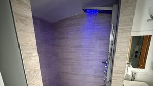 A modern bathroom with a shower, a sink, and a mirror. -  Four Bedroom Woodland Retreat Near Downtown Wisconsin Dells! (Wisconsin Dells)