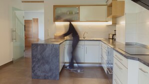 Een moderne keuken met een marmeren aanrechtblad, houten kastjes en een RVS-spoelbak.