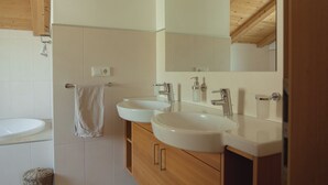 Een badkamer met twee wastafels, een spiegel en houten kastjes.