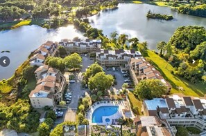 An aerial view of a residential area with a swimming pool, surrounded by greenery and a lake. - Luxury Condo, Waterviews, Pools, 12PM Check In (Myrtle Beach)