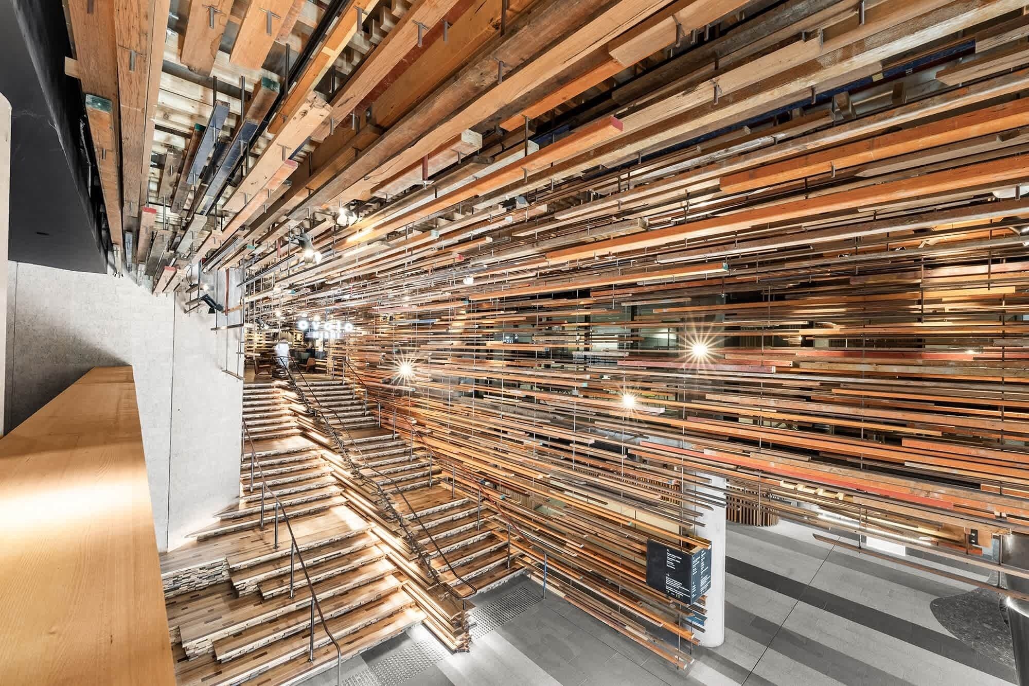 A warehouse with wooden beams stacked in rows, metal railings, and a concrete floor.
