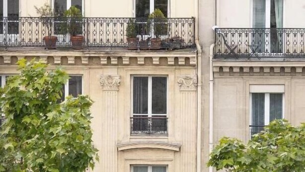 A row of multi-story buildings with balconies, windows, and some greenery. - Suite elegante entre Tour Eiffel et Invalides (Paris)