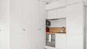 A modern kitchen with white cabinetry, a microwave, a coffee maker, and a stainless steel oven. - Suite elegante entre Tour Eiffel et Invalides (Paris)