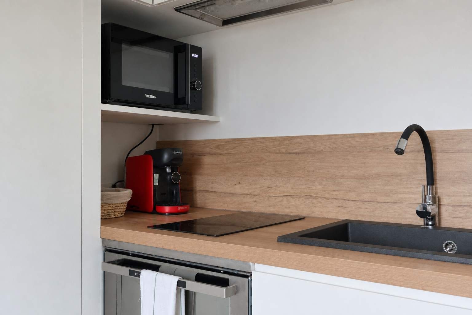 A modern kitchen with a built-in microwave, a coffee maker, and a stainless steel sink.