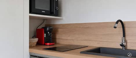 A modern kitchen with a built-in microwave, a coffee maker, and a stainless steel sink.