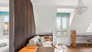 A modern living room with a sofa, a coffee table, a tall woven sculpture, and a chandelier. - Suite elegante entre Tour Eiffel et Invalides (Paris)