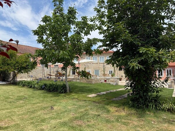 A stone building with a garden, outdoor seating, and a pathway.
