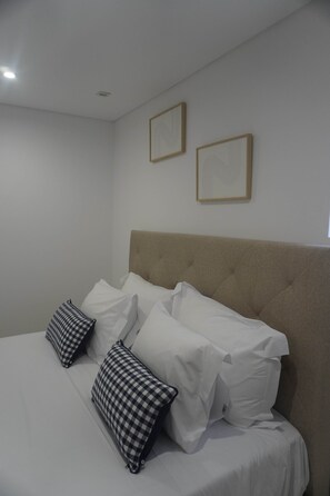A neatly made bed with white and checkered pillows, a beige headboard, and two framed artworks on the wall. - Solar dos Caseiros B (Macieira da Maia)