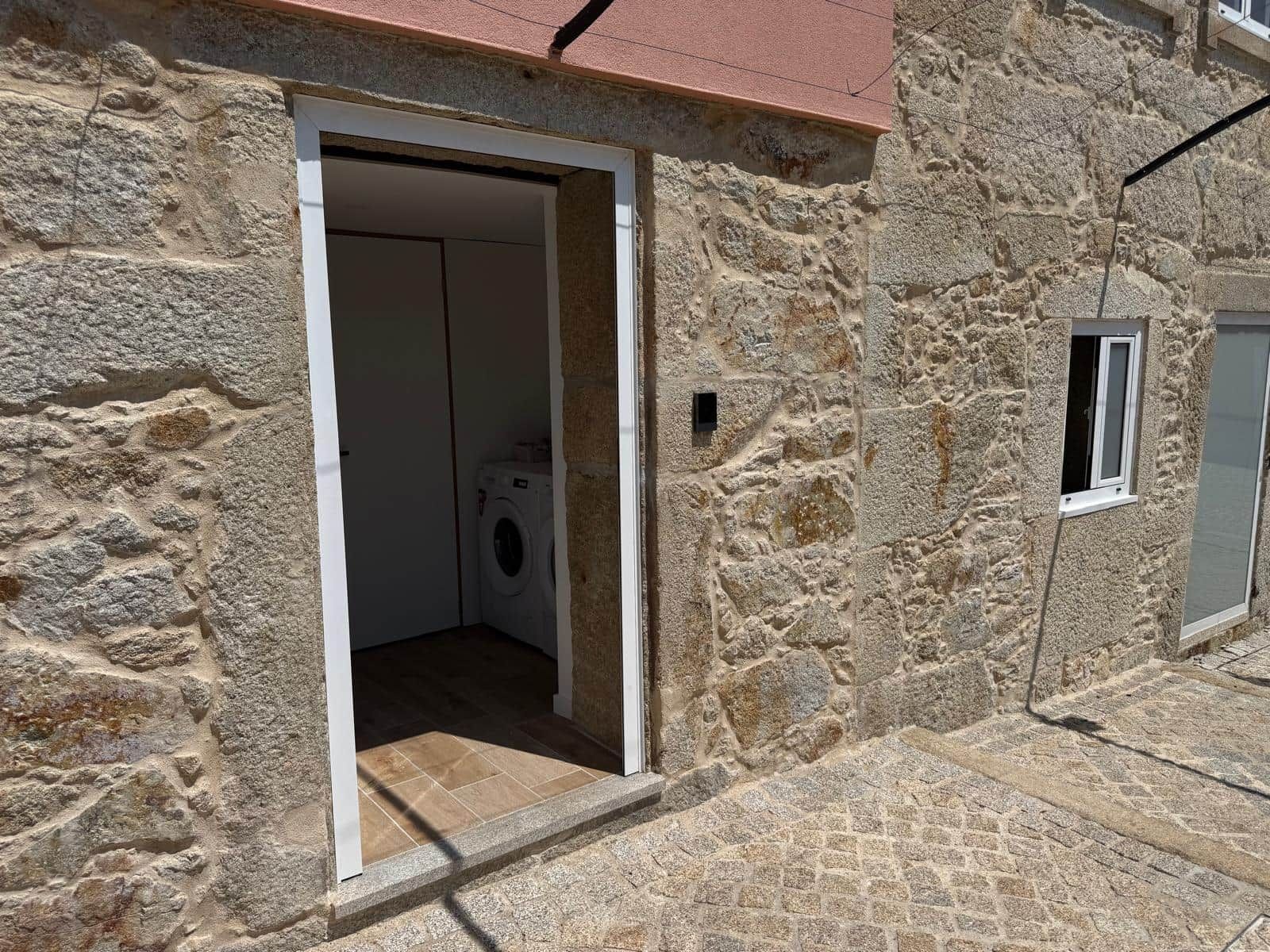 A stone building with a laundry room visible through an open doorway.