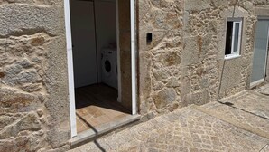 Un edificio de piedra con un lavadero visible a través de un acceso abierto.