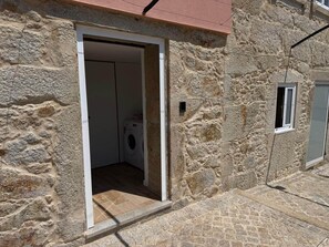 A stone building with a laundry room visible through an open doorway. - Family-friendly apartment, next to event venues (Macieira da Maia)