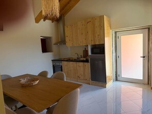 Une cuisine avec des meubles en bois, un four à micro-ondes et un lave-vaisselle. On y trouve une table à manger avec des chaises et un panier.