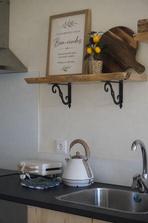 A kitchen with a wooden shelf holding a framed sign, a kettle, and a toaster. - Family-friendly apartment with a pool on Caminho Santiago (D) (Macieira da Maia)