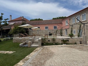 A stone pathway leading to a pool area with outdoor furniture and umbrellas. - Family-friendly apartment with a pool on Caminho Santiago (D) (Macieira da Maia)