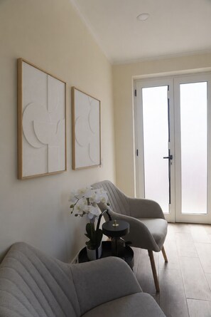 A living room with a sofa, a chair, a small table with a plant, and two abstract wall art pieces. - Solar dos Caseiros D (Macieira da Maia)